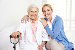 A Female Nurse and female elderly patient are sitting down and smiling